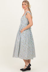 woman wearing a sleeveless light blue floral midi dress with pockets and a fitted bodice