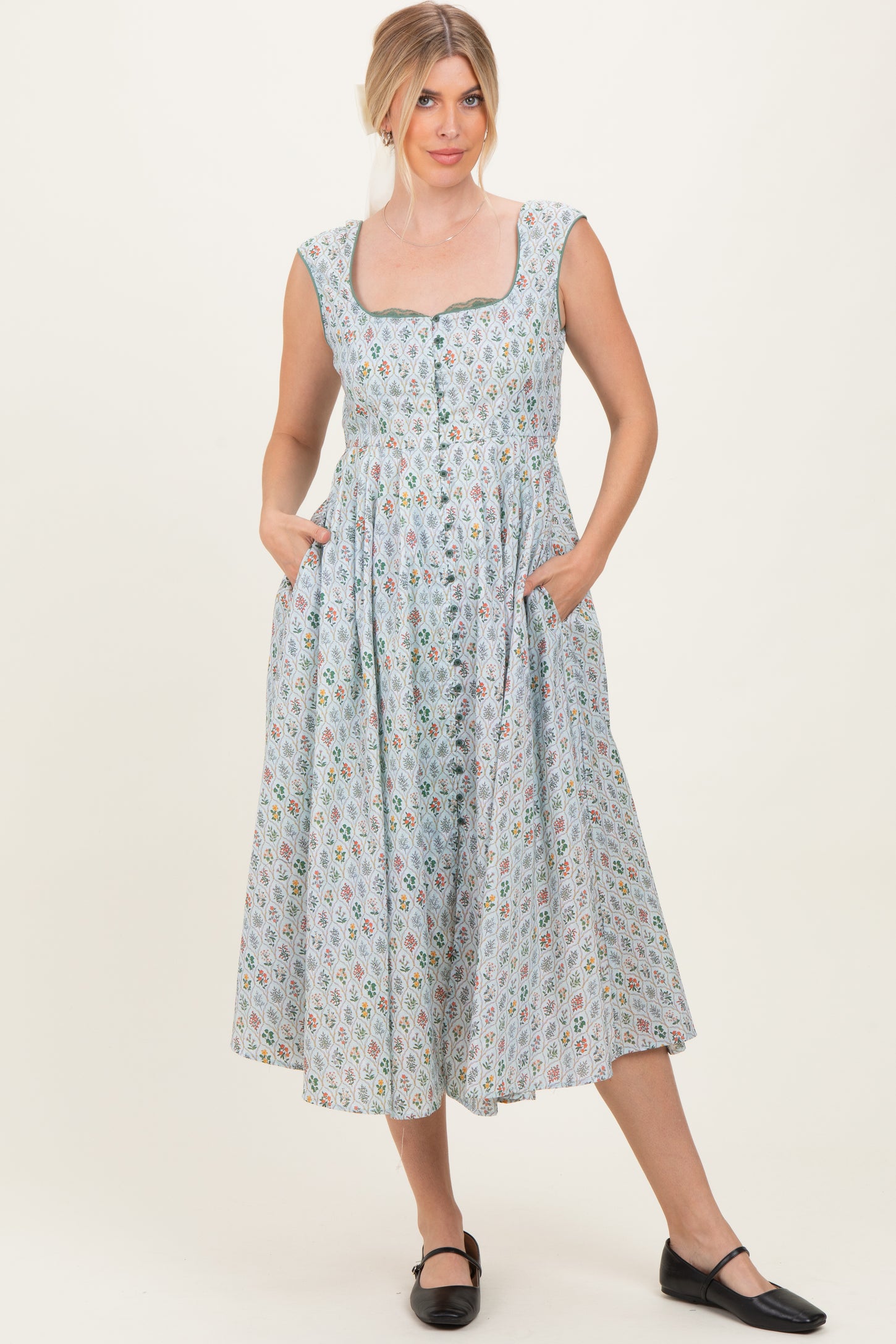 woman wearing a light blue floral midi dress with cap sleeves and pockets