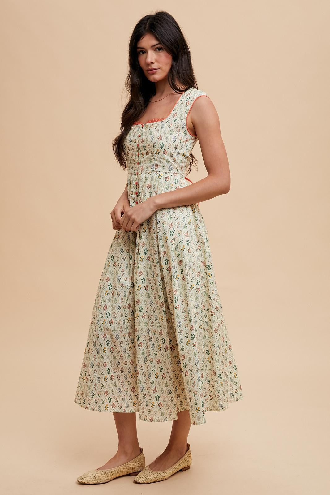 woman wearing a floral midi dress with a fitted bodice and flared skirt, paired with flat woven sandals