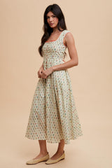 woman wearing a floral midi dress with a fitted bodice and flared skirt, paired with flat woven sandals