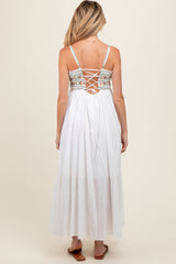 woman wearing a white maternity maxi dress with a floral embroidered back and lace-up detail