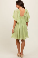 woman wearing a light green maternity dress with flutter sleeves and a scoop back
