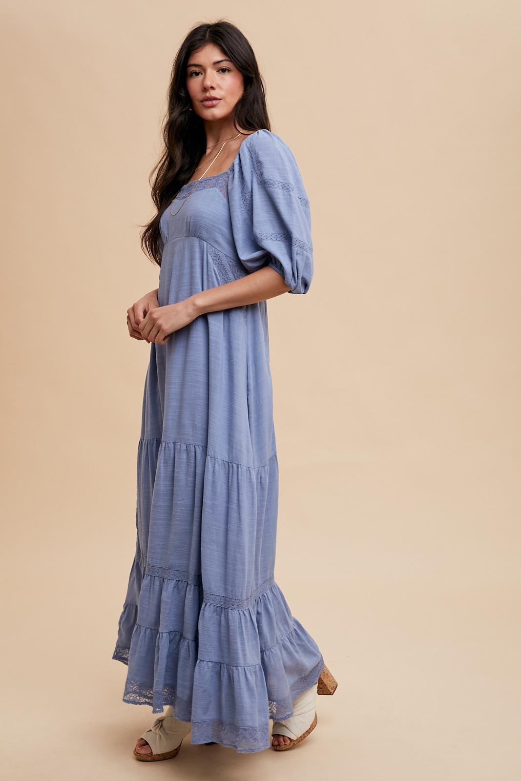 woman wearing a light blue puff sleeve maxi dress with tiered detailing and lace trim