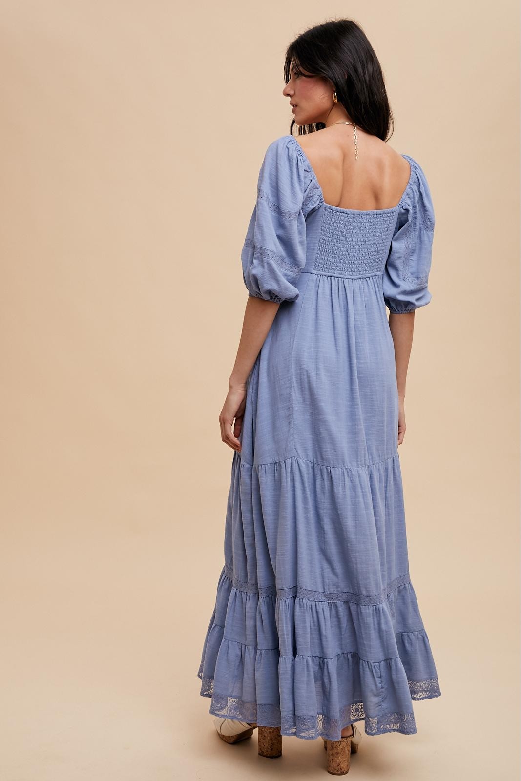 woman wearing a light blue puff sleeve maxi dress with a smocked back and tiered ruffle hem