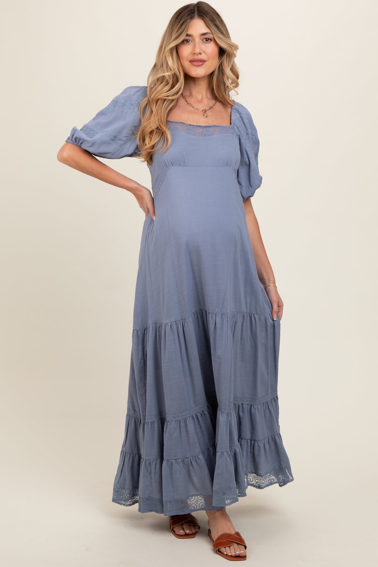 woman wearing a light blue tiered maternity dress with puff sleeves and a baby bump visible