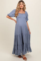 woman wearing a light blue tiered maternity dress with puff sleeves and a baby bump visible