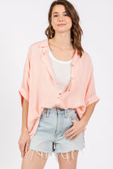 woman wearing a coral and white striped oversized button-up shirt with rolled sleeves and distressed denim shorts