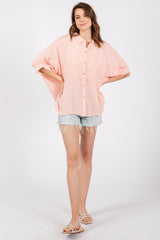 woman wearing a pink and white striped oversized button-down shirt with rolled sleeves and denim shorts
