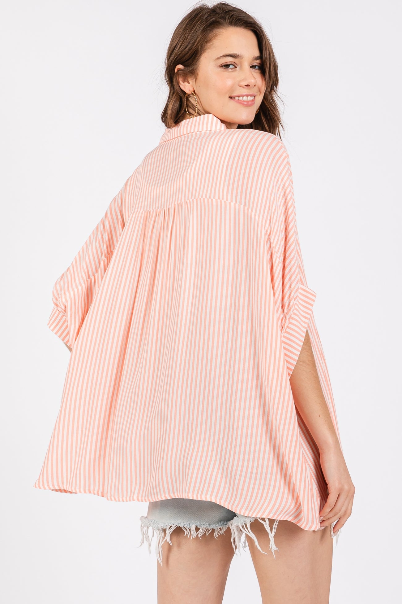 woman wearing a striped peach and white oversized kimono top with short sleeves and a relaxed fit