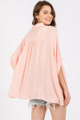 woman wearing a striped peach and white oversized kimono top with short sleeves and a relaxed fit