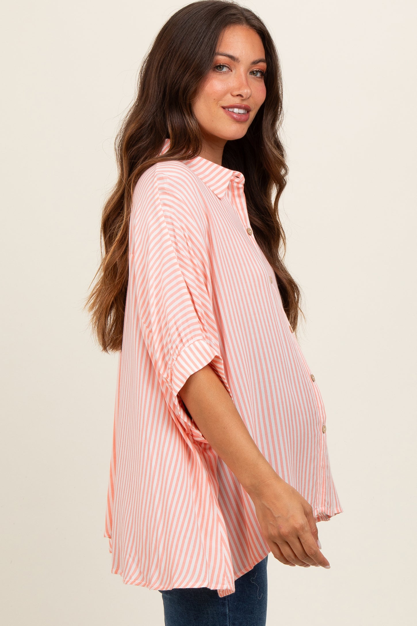 woman wearing a light pink and white striped maternity shirt with buttons and a visible baby bump