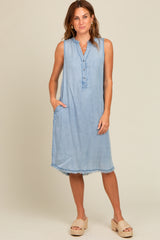 woman wearing a light wash sleeveless denim dress with a button-down front and frayed hem, displaying side pockets