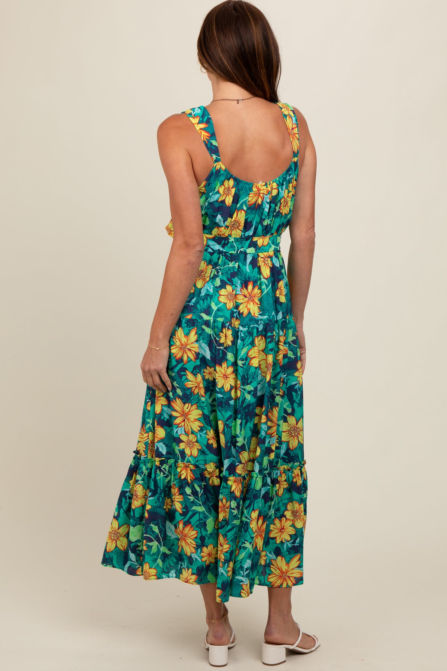 woman wearing a blue floral maxi dress with yellow and green patterns, showing a back view