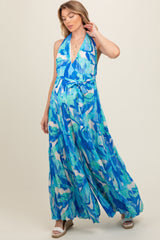 woman wearing a blue and green floral halter maternity maxi dress with a tied waist detail and a flowing silhouette