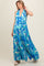 woman wearing a blue and green floral halter maternity maxi dress with a tied waist detail and a flowing silhouette