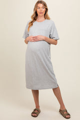 woman wearing a gray short sleeve maternity dress, showcasing her baby bump