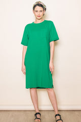 woman wearing a bright green short sleeve oversized dress with a pocket and side slits