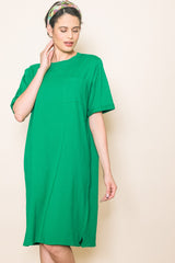 woman wearing a loose-fitting green t-shirt dress with short sleeves and a chest pocket