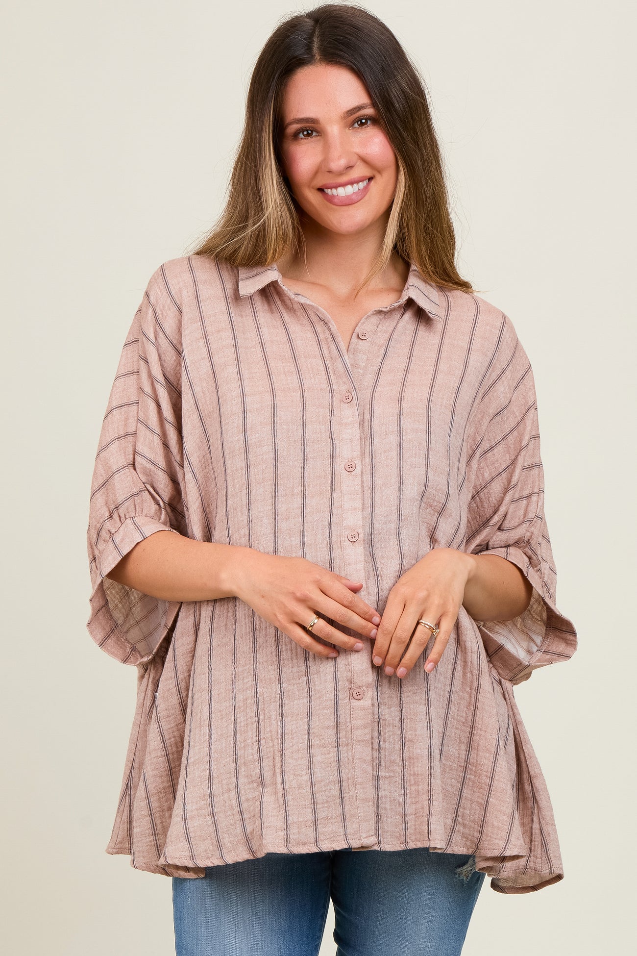 woman wearing a light pink striped maternity top with button details and a relaxed fit