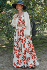 woman wearing a white floral maxi skirt and matching crop top with a knitted cardigan and wide-brimmed hat
