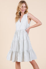 woman wearing a white and navy striped sleeveless tiered dress with a v-neckline and flowy silhouette
