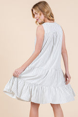 woman wearing a sleeveless white and gray striped tiered dress, twirling to show the flared hem and relaxed fit