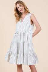 woman wearing a white and black striped sleeveless tiered dress with a v-neckline and relaxed fit