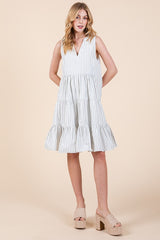 woman wearing a sleeveless white striped tiered dress with a v-neck and tan platform sandals