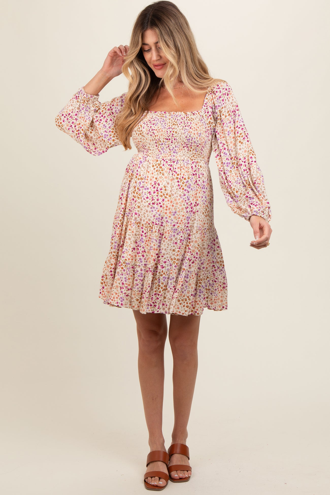 woman wearing a floral print maternity dress with a smocked bodice and long sleeves, showing her baby bump