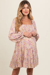 woman wearing a floral print maternity dress with a square neckline and tiered skirt, showing her baby bump