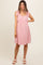 woman wearing a pink maternity dress with tie shoulder straps and an empire waist, showcasing her baby bump