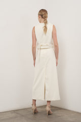 woman wearing a cream sleeveless dress with a back tie detail and a high slit, styled with strappy heels