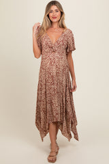 woman wearing a patterned brown maternity dress with a v-neckline and flutter sleeves, showing her baby bump