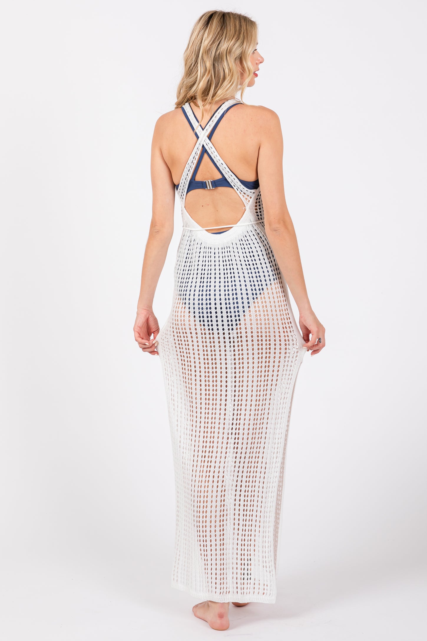 woman wearing a white crochet cover-up with a crisscross back over a swimsuit