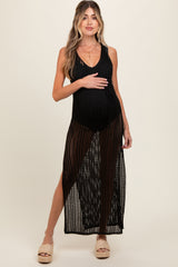 woman wearing a black open knit maternity cover-up dress with a side slit and holding her baby bump
