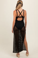 woman wearing a black open-knit maternity cover-up with crossback straps and side slits