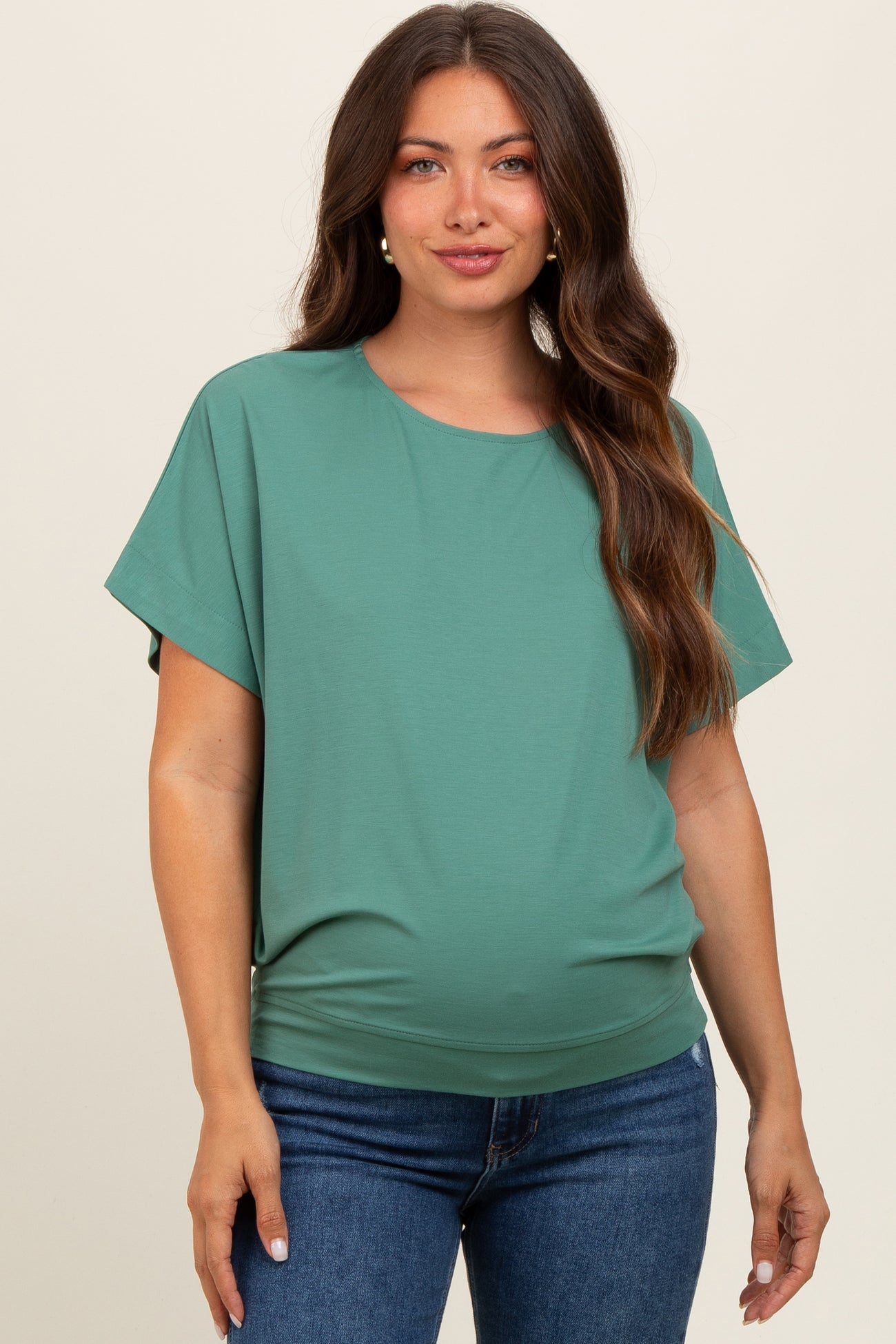 woman wearing a green short sleeve maternity top with a loose fit and a visible baby bump