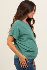 woman wearing a green short sleeve maternity top with a visible baby bump