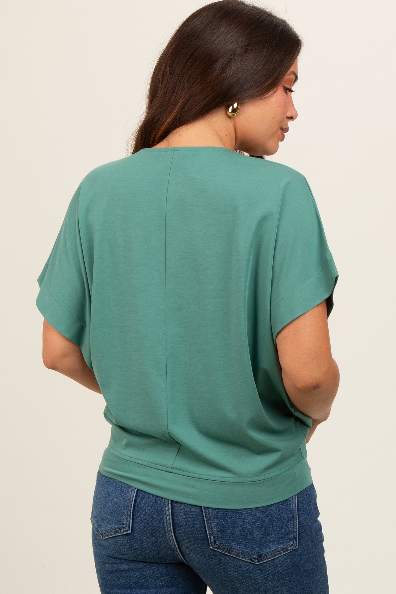 woman wearing a teal maternity top with short sleeves and a relaxed fit, showing her back