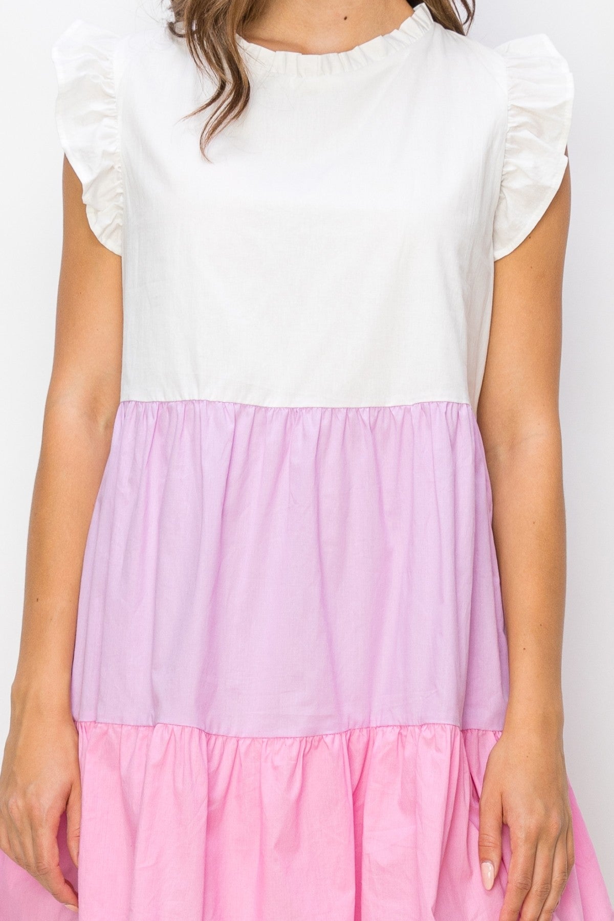 woman wearing a color-blocked dress with white top and pink and purple tiered skirt