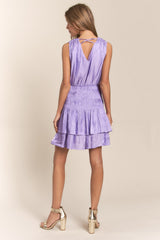 woman wearing a lilac sleeveless tiered dress with a smocked waist and crisscross back detail