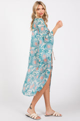 woman wearing a teal floral kimono with open sides and a tie waist, styled over a casual outfit