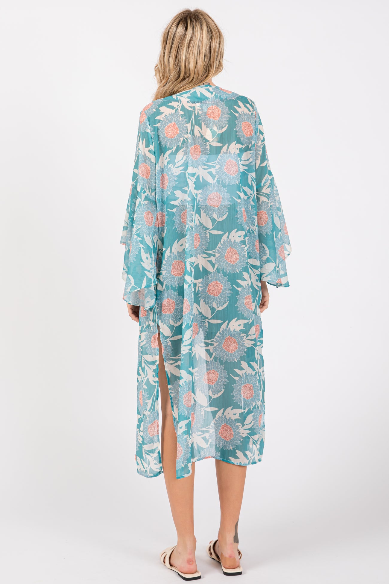 woman wearing a teal floral kimono with wide sleeves and side slits, seen from the back