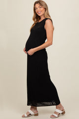 woman wearing a black ribbed maternity maxi dress and cradling her baby bump