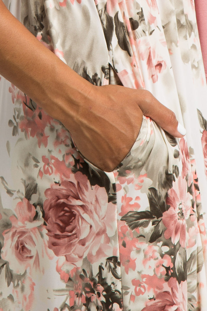 Close up of a hand in the pocket of a white floral print dress with pink roses and a drawstring waist