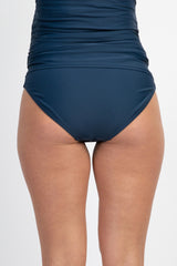 woman wearing a navy blue maternity swim bottom with a high-waisted design and gathered side details