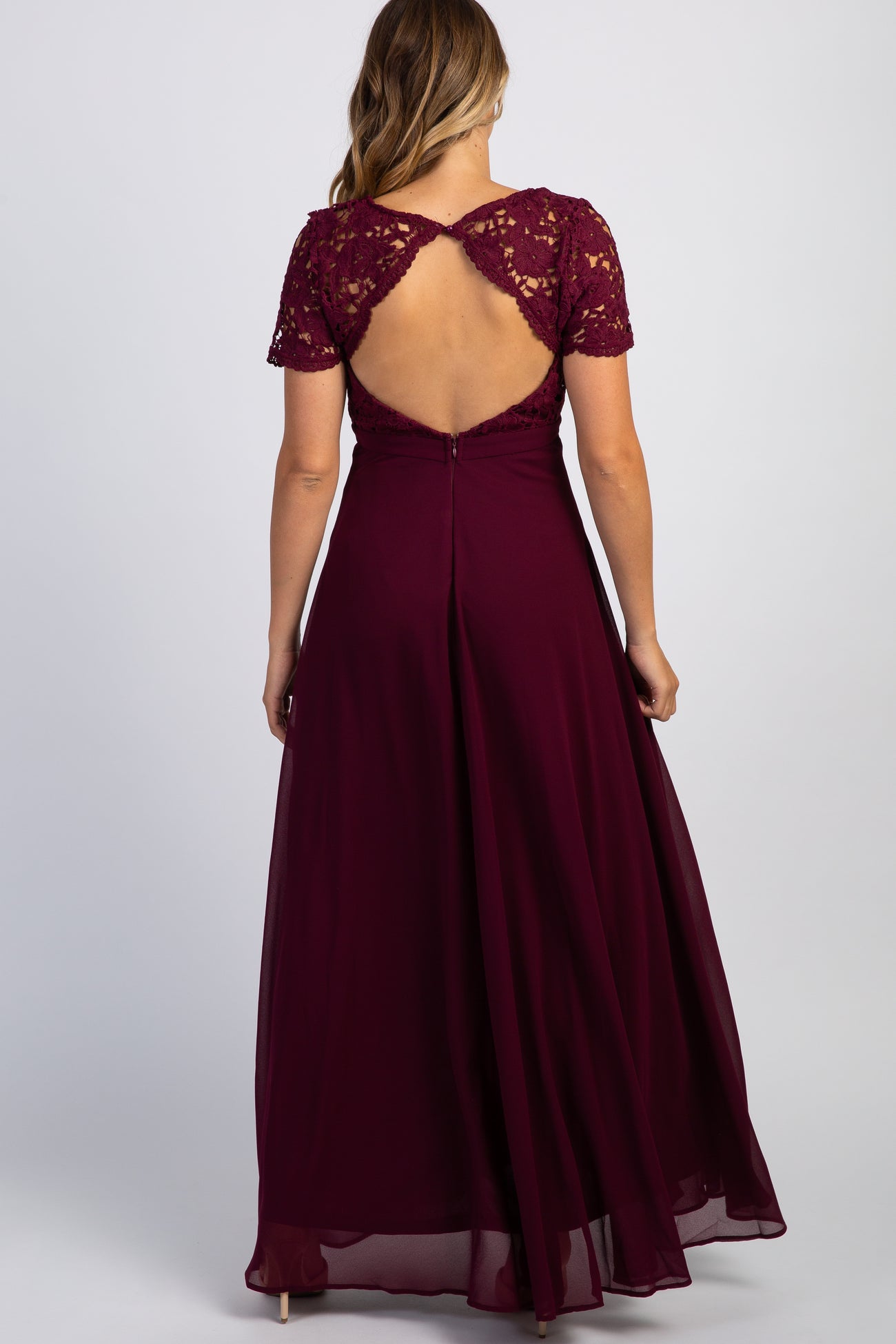 Back view of a woman wearing a burgundy maxi dress with a lace bodice and open back cutout