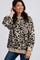 woman wearing a tan and black leopard print oversized knit sweater with blue jeans