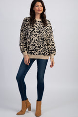 woman wearing a tan and black leopard print sweater with dark blue skinny jeans and brown suede ankle boots