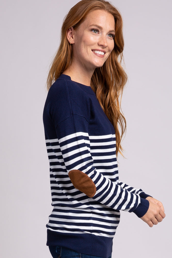 smiling woman wearing a navy and white striped sweater with brown suede elbow patches